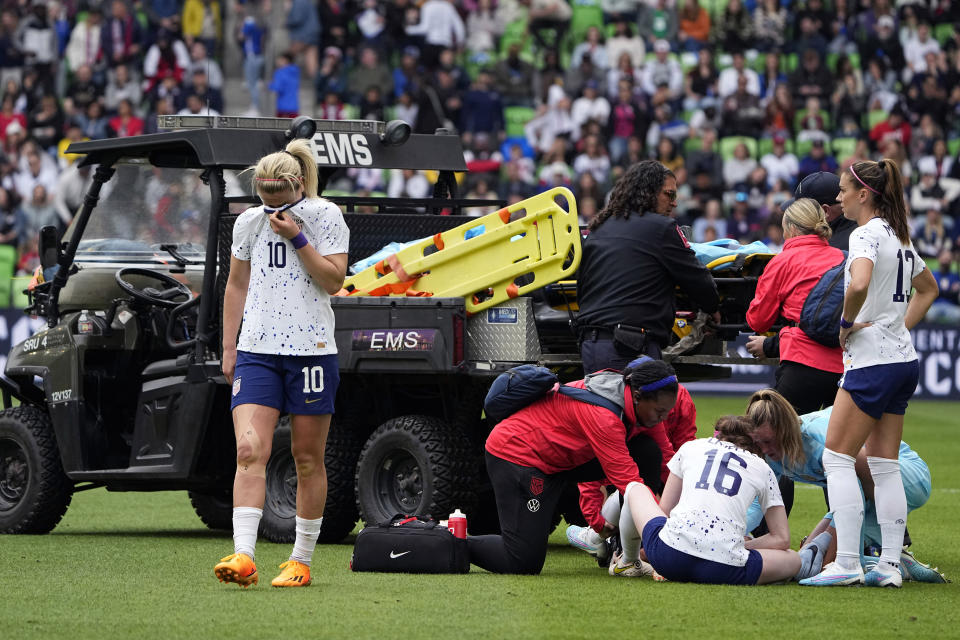 United States midfielder Lindsey Horan (10) and other players stands by as teammate Mallory Swanson receives medical attention after an injury in the first half of an international friendly soccer match against Ireland in Austin, Texas, Saturday, April 8, 2023. (AP Photo/Eric Gay)