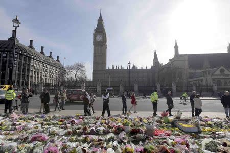 A police officer looks at floral tributes in Parliament Square, following the attack in Westminster earlier in the week, in London, Britain March 25, 2017. REUTERS/Paul Hackett