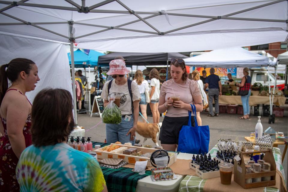 Alpine Aromatics Sarah Miller, from left, and Aiden Duggan talk with customers Maddy Kling and Grace Cooper, right, at their booth at the Larimer County Farmers' Market in Fort Collins on June 18.