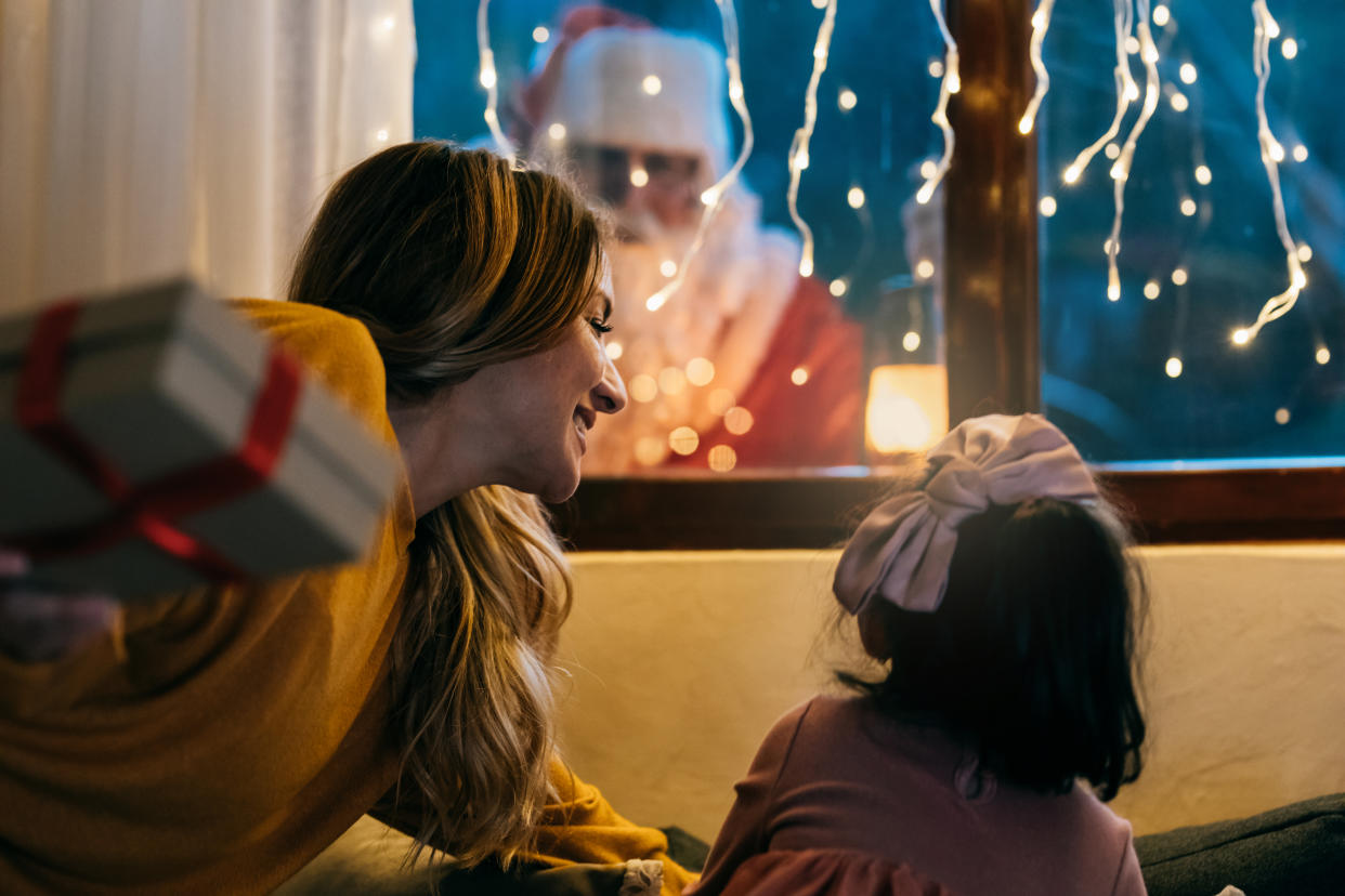 A mom and young daughter see Santa outside their window