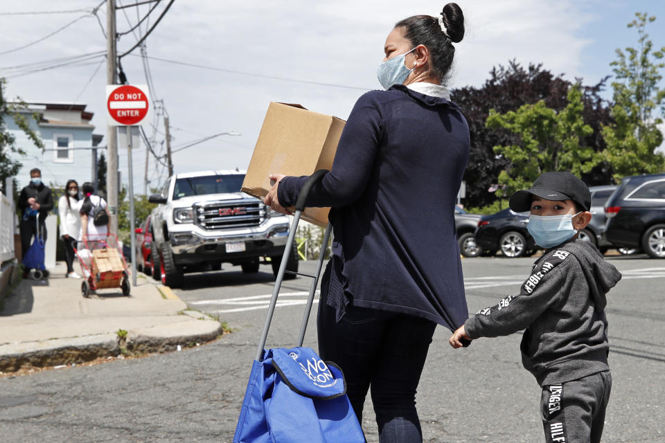 A woman and young boy walk away Tuesday, June 2, 2020 after receiving a box of food at a pop-up pantry in Chelsea, Mass. (AP Photo/Elise Amendola)