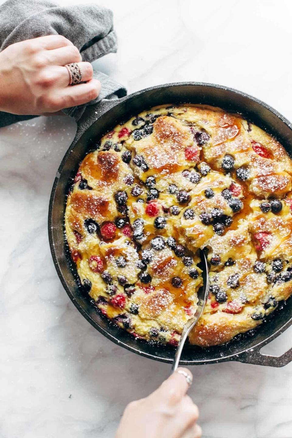 French toast casserole being scooped out of a cast iron skillet