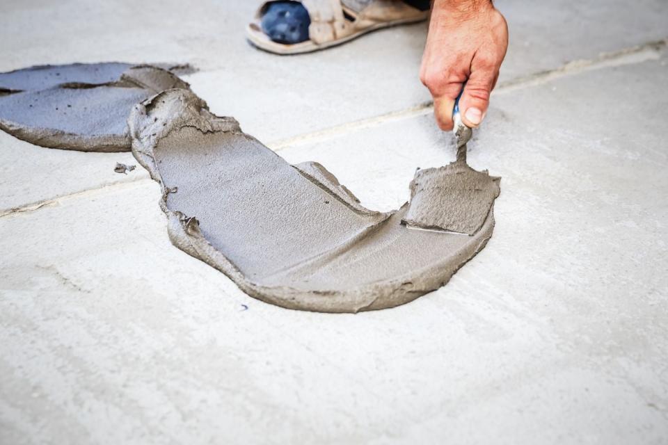 A close up of a hand spreading concrete. 