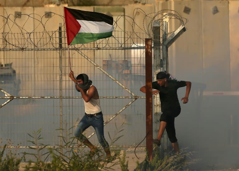 A Gazan holds aloft a Palestinian flag as he runs through tear gas fired by Israeli forces during a protest at the Erez crossing on September 4, 2018, that prompted Israel to close it for more than a week