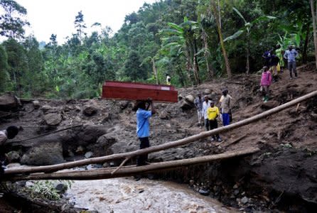 FILE PHOTO: A man crosses the Sume river carrying an empty coffin on his head after a landslide rolled down the slopes of Mt. Elgon through their village of Wanjenwa in Bududa district, Uganda, October 13, 2018. REUTERS/Newton Nambwaya/File Photo