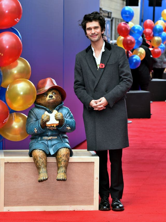 A statue of Paddington Bear eating a sandwich alongside actor Ben Wishaw