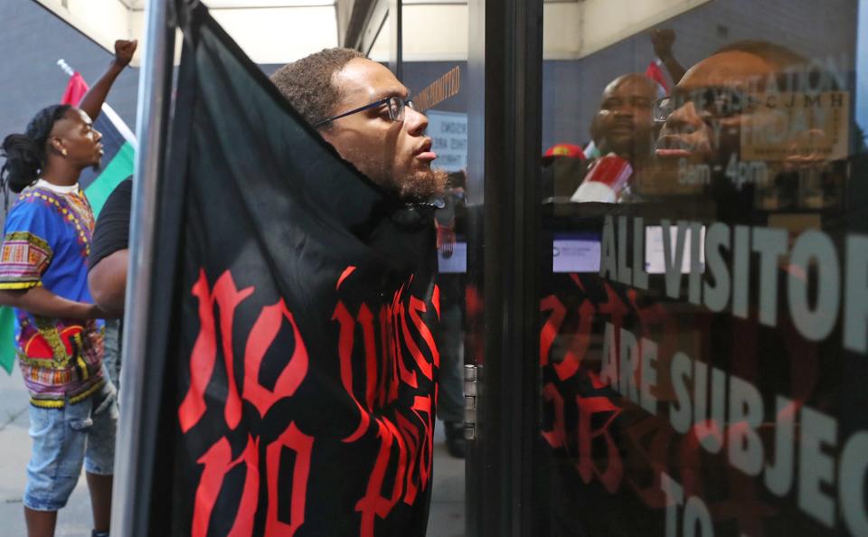 James Crawl, 25, holds a "No Justice No Peace" flag at the entrance of Summit County Jail during a protest Tuesday.