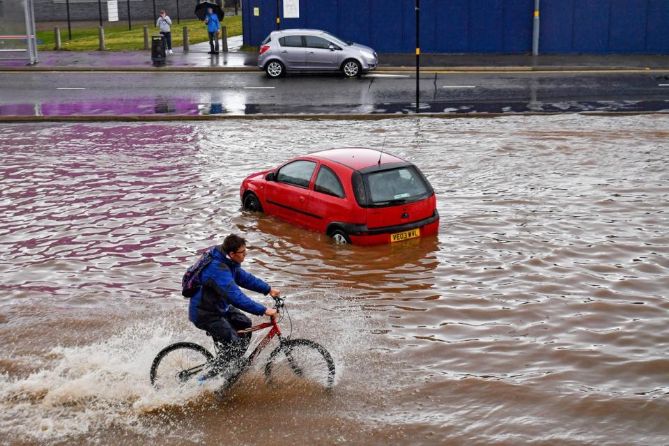 A man cycles past a stranded car on a flooded road in Birmingham 