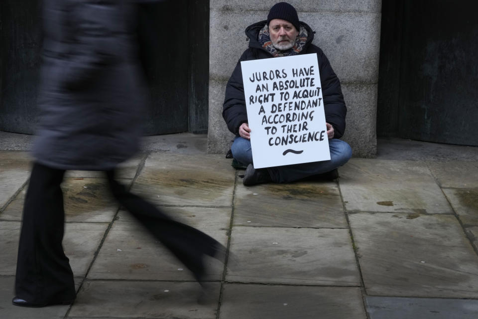 A demonstrator holds a banner outside The Old Bailey, the Central Criminal Court of England and Wales, in London, Monday, Dec. 4, 2023. An estimated 500 people are expected to gather outside Crown Courts nationwide to protest. Britain is one of the world's oldest democracies, but some worry that essential rights and freedoms are under threat. They point to restrictions on protest imposed by the Conservative government that have seen environmental activists jailed for peaceful but disruptive actions. (AP Photo/Kirsty Wigglesworth)