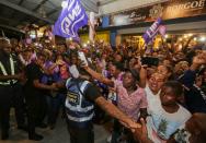 Supporters of Suriname's President Desi Bouterse (not pictured), who was convicted of murder for the execution of opponents by a court in Suriname, cheer upon his arrival from China, in Paramaribo