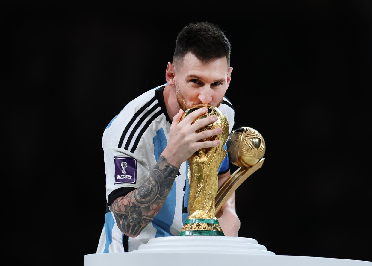 LUSAIL CITY, QATAR - DECEMBER 18: Lionel Messi of Argentina kisses the FIFA World Cup Qatar 2022 Winners' Trophy while holding the adidas Golden Boot award after the FIFA World Cup Qatar 2022 Final match between Argentina and France at Lusail Stadium on December 18, 2022 in Lusail City, Qatar. (Photo by Maja Hitij - FIFA/FIFA via Getty Images)