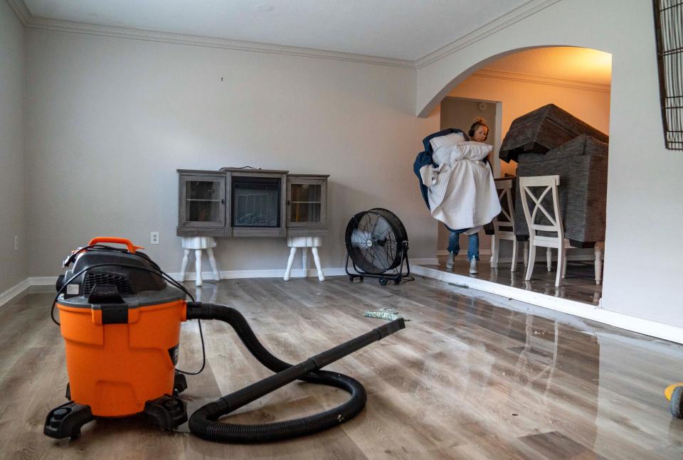 Mary Kate Norrie carries items from her bedrooom that she salvaged from the flooding from Hurricane Idalia in Crystal River, Florida on August 31, 2023. The home is unlivable after the flooding damages the floors, drywall and carpet.