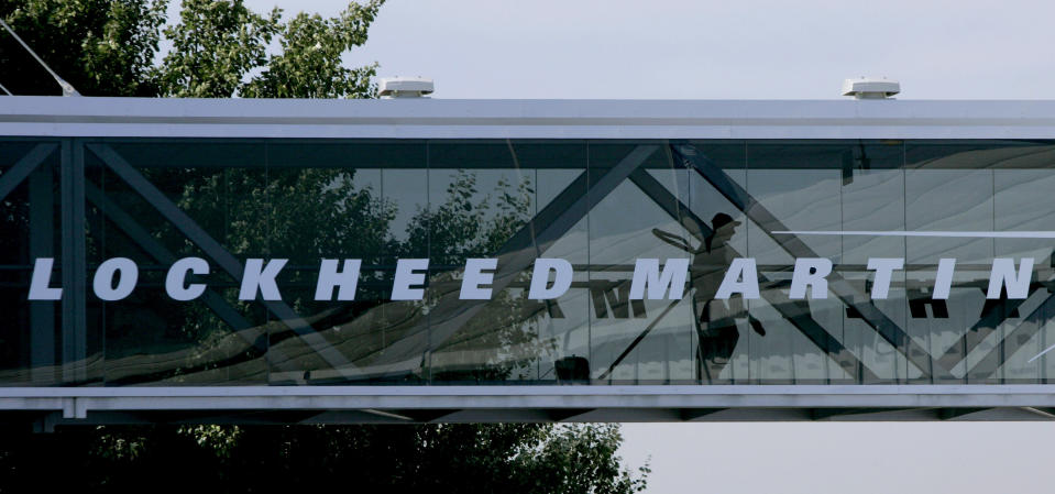 FILE - A man walks past a Lockheed Martin logo as he walks through a section of the company's chalet bridging a road at Farnborough International Airshow in Farnborough, southern England, July 19, 2006. Two Lockheed Martin subsidiaries have agreed to pay the federal government $70 million for overcharging the Navy for aircraft parts, the U.S. Department of Justice announced Friday, June 21, 2024. (AP Photo/Matt Dunham, File)