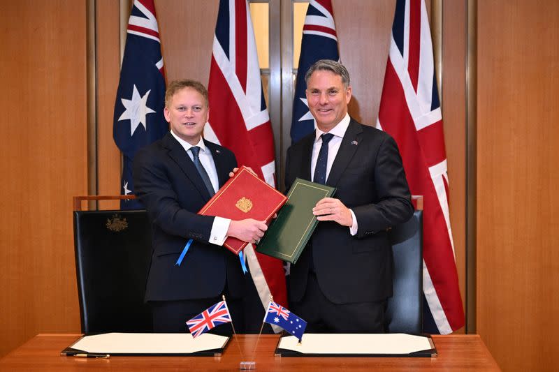 Secretary of State for Defence of the UK Shapps and Australian Defence Minister Marles exchange Defence Treaty documents during a meeting in Canberra