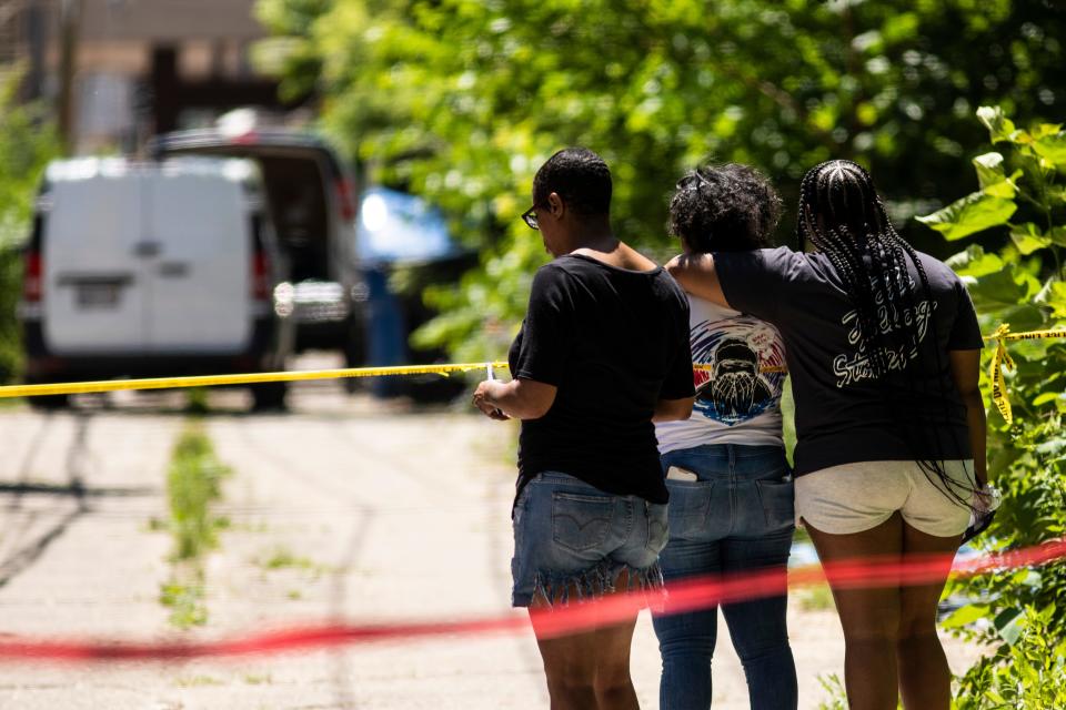 People watch as officials remove four bodies from a house on South Morgan Street in Chicago's South Side on Tuesday, June 15, 2021.
