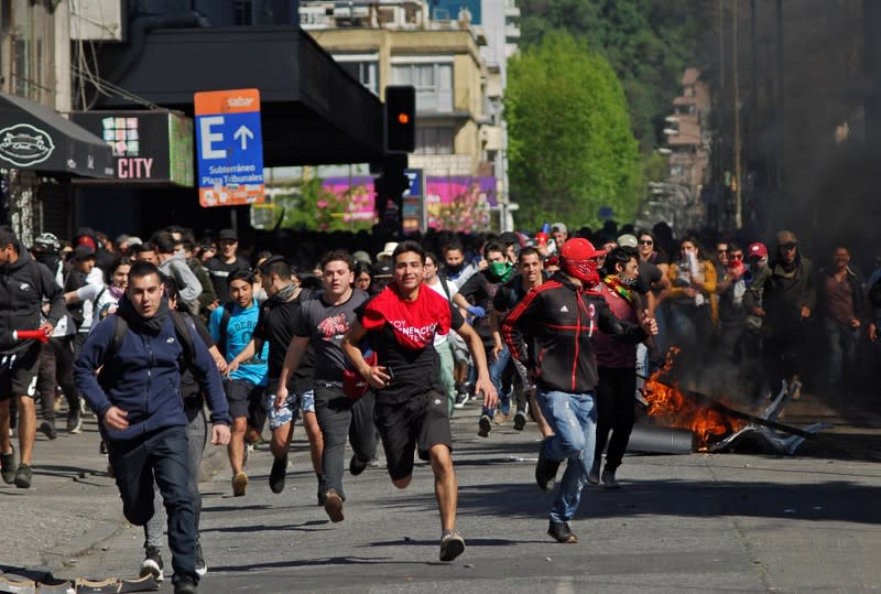 Demonstrators run away from officers of the Chilean police (Carabineros) during a protest against social inequality in Concepcion