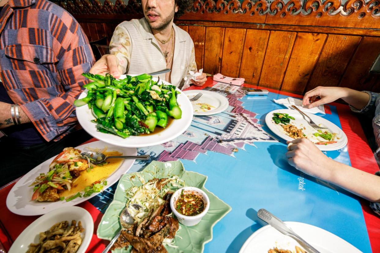 Benny Blanco passes food at Spicy BBQ Restaurant.