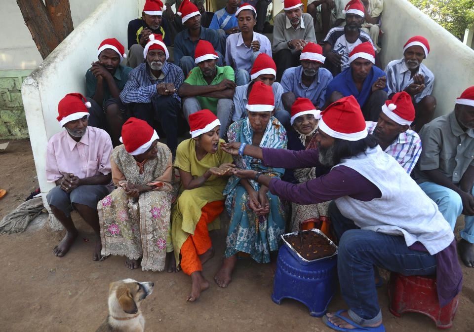 George Rakesh Babu, right, founder of Good Samaritans India, a non-government organization feeds food to a homeless person at a shelter to celebrate Christmas on the outskirts of Hyderabad, India, Friday, Dec. 25, 2020. (AP Photo/Mahesh Kumar A.)