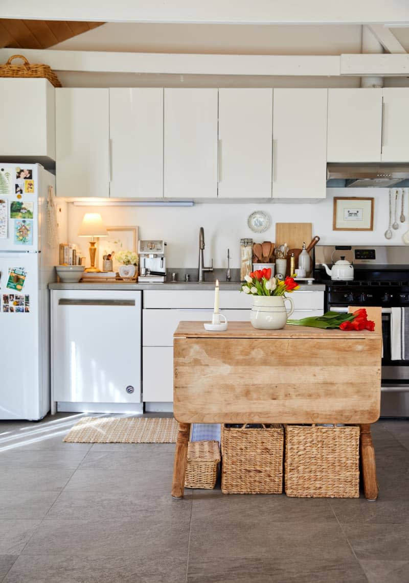 A kitchen with butcher block island and white cabinets.