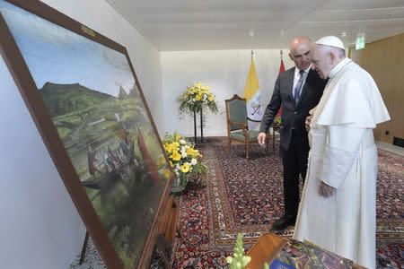 Pope Francis looks at a painting next to Swiss president Alain Berset, after his arrival in Geneva, Switzerland June 21, 2018. Vatican Media/Handout via REUTERS