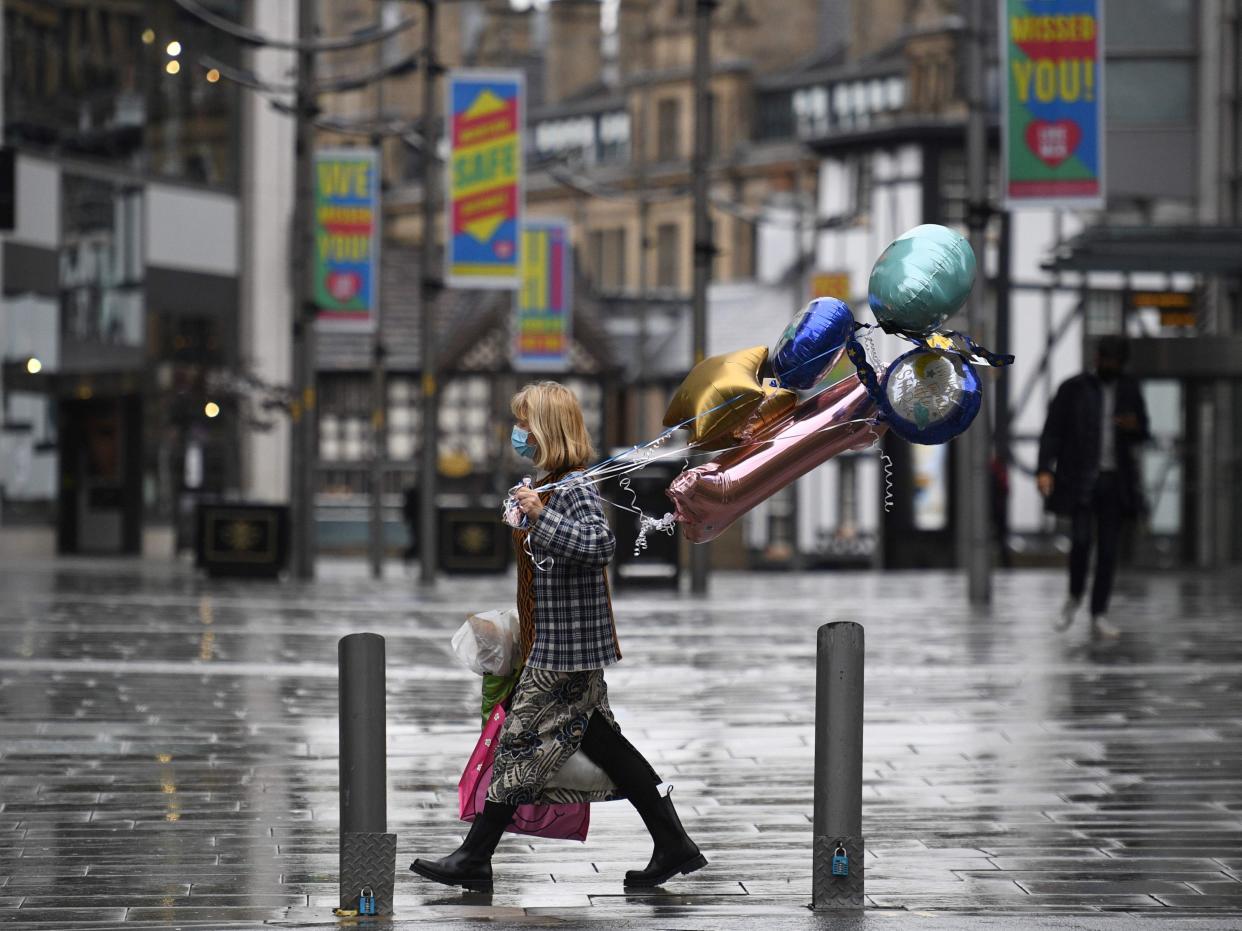 A shopper wears a facemask as she walks along a near-deserted street in Manchester, north west England (AFP via Getty Images)