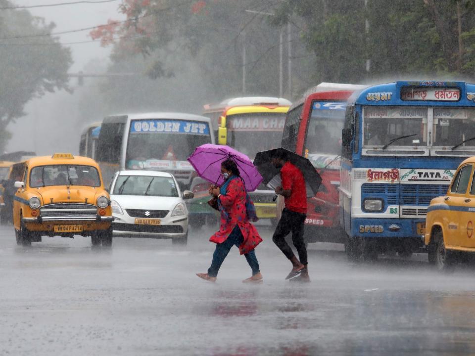 two people cross a busy street holding umbrellas in the rain