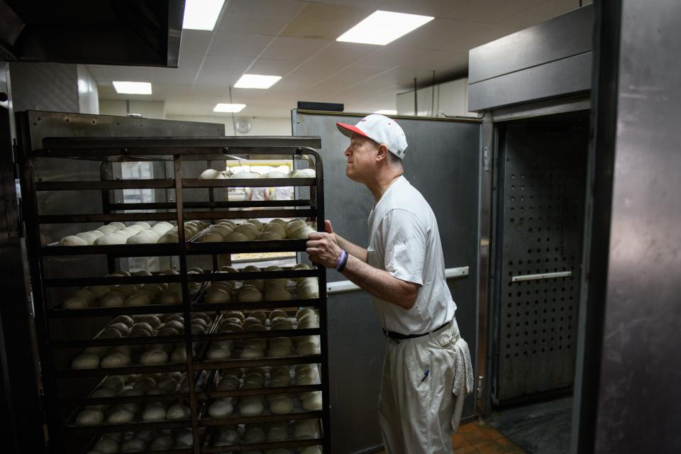 Nick Poulos moves a rack of rolls into an oven at Superior Bakery on Wednesday, April 19, 2023.