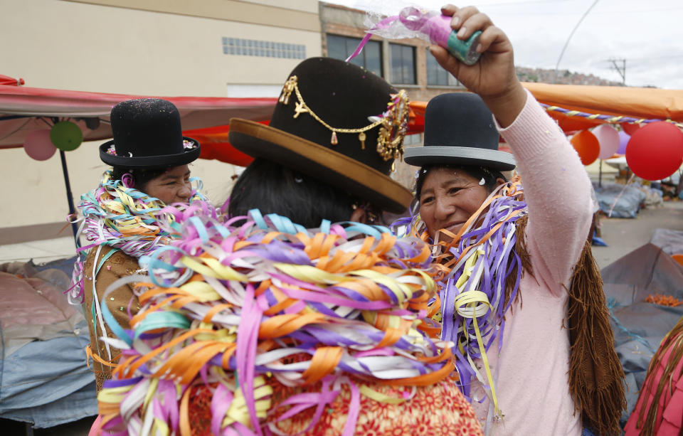 Aymara Indian women wrap each other with streamers as part of a ceremony called "Challa" during carnival celebrations at a street market in La Paz, Bolivia, Tuesday Feb. 17, 2015. Challa is an indigenous offering that symbolizes giving a first sip of drink to Mother Earth, or Pachamama in Aymara, to give thanks and quench her divinity's thirst. (AP Photo/Juan Karita)