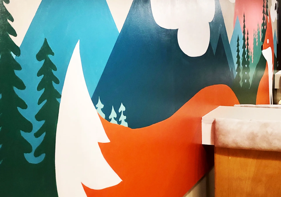 A fox in a forest is painted on a wall in a bold style.