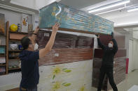Wilson Tong, CEO of LifeArt Asia, left, and a worker move a blue floral coffin on top of other paper coffins at the factory in Hong Kong, Friday, March 18, 2022. Hong Kong is running short of coffins during its deadliest outbreak of the coronavirus pandemic. LifeArt, a company in Hong Kong is trying to make an alternative, cardboard coffin, which it says is environmentally-friendly. (AP Photo/Kin Cheung)