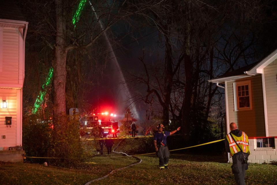 Fire and police officials walk around the scene of a house explosion as an Arlington County Fire Department ladder truck sprays water down on the remains of the building on Monday, Dec. 4, 2023, in Arlington, Va. (AP)
