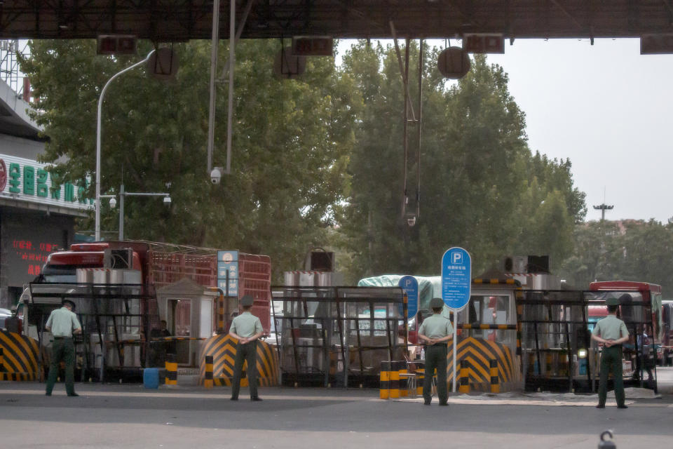 Chinese paramilitary police stand guard at barricaded entrances to the Xinfadi wholesale food market district in Beijing, Saturday, June 13, 2020. Beijing closed the city's largest wholesale food market Saturday after the discovery of seven cases of the new coronavirus in the previous two days. (AP Photo/Mark Schiefelbein)