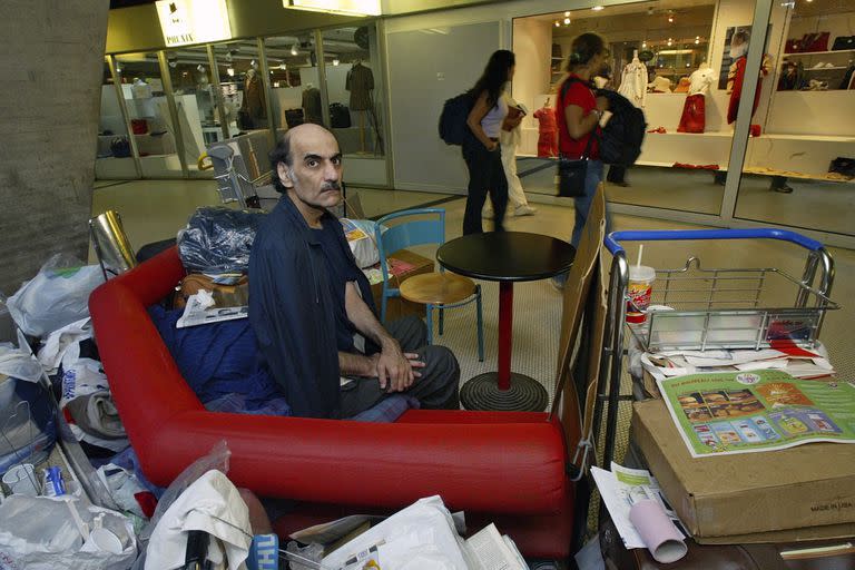 Merhan Karimi Nasseri sentado entre sus pertenencias en la Terminal 1 del aeropuerto Roissy Charles De Gaulle, en París, el 11 de agosto de 2004
