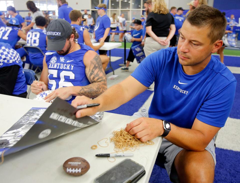 Coach Jon Sumrall, right, signs autographs during Kentucky football's Fan Day at the Nutter Field House on campus.