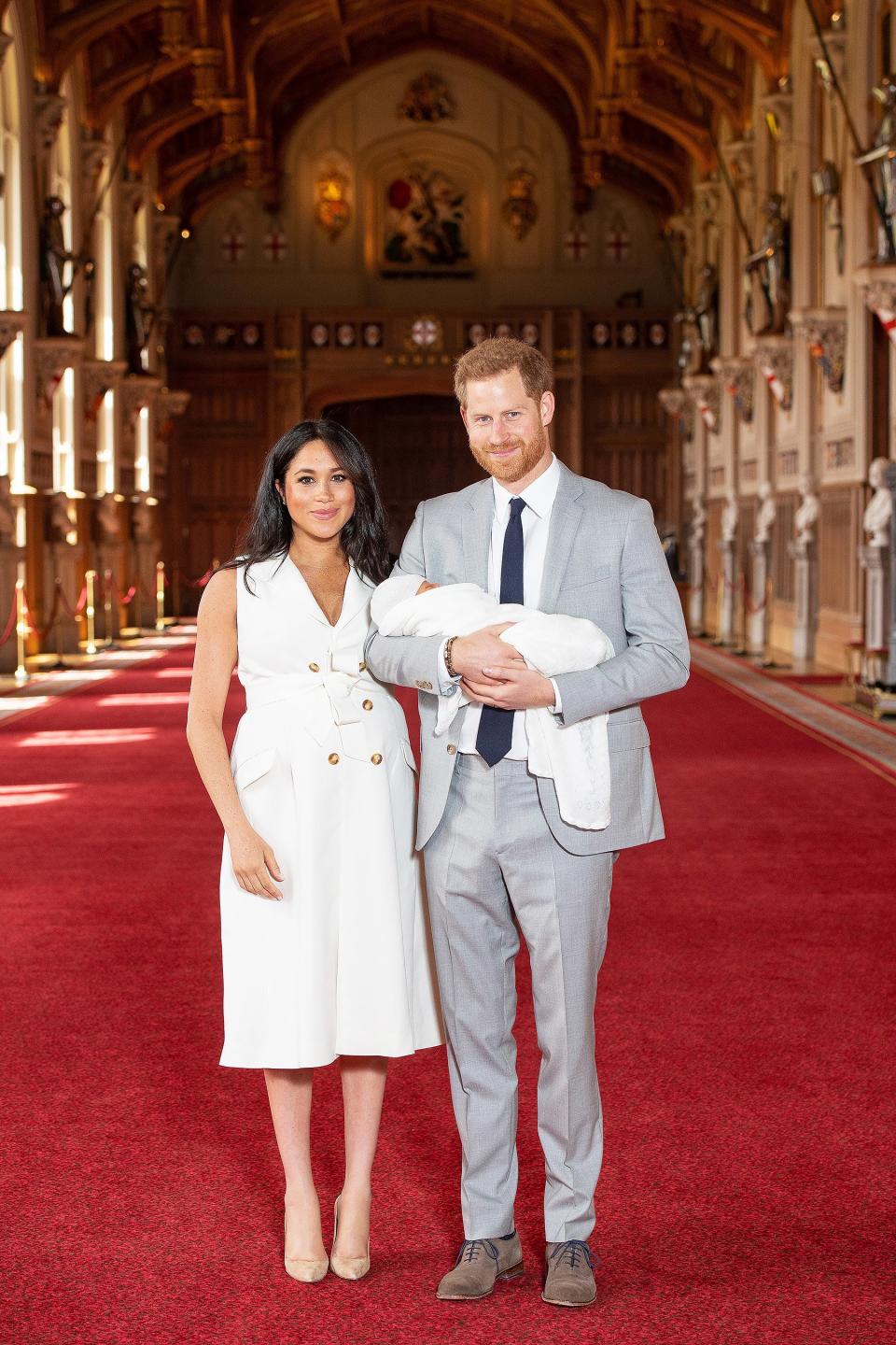 Meghan made her mommy debut in a favorite style: a white trench dress tied at the waist with a bow.