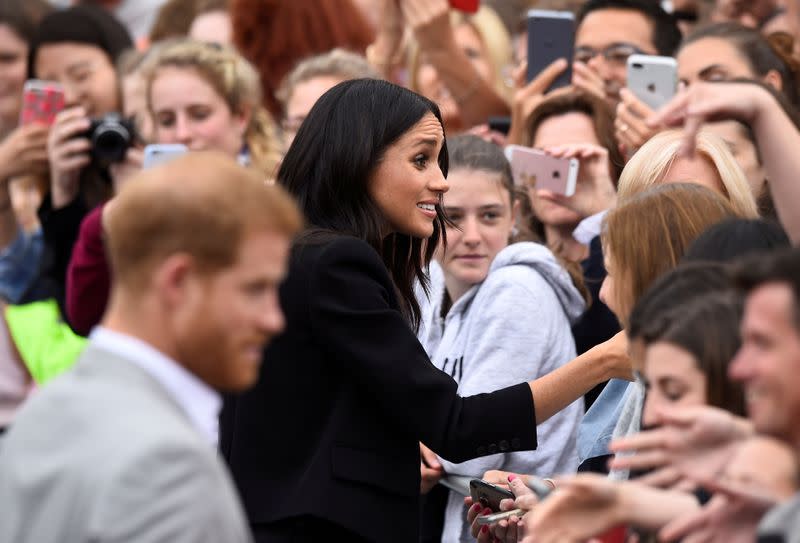 FILE PHOTO: Britain's Prince Harry and Meghan, the Duchess of Sussex, shake hands with members of the crowd during a walkabout in Parliament Square in Trinity College, Dublin