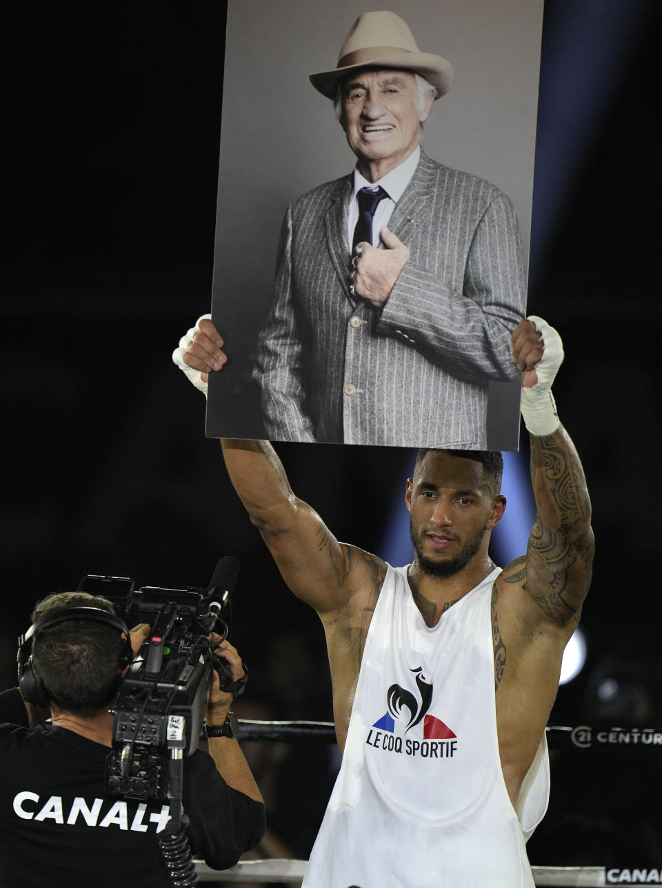 Tony Yoka of France holds up a photo of late French actor Jean-Paul Belmondo after he defeated Croatia's Petar Milas in a heavyweight boxing fight on the central court Philippe Chatrier at the Roland Garros tennis stadium, in Paris, Friday, Sept. 10, 2021. Belmondo a boxing enthusiast and former amateur boxer died earlier this week aged 88 (AP Photo/Francois Mori)