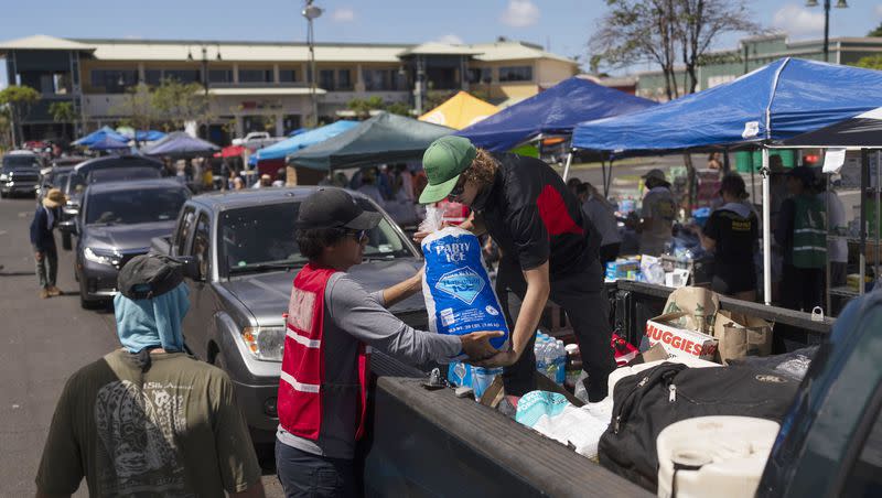 Volunteers work at a food distribution center set up in the parking lot of a shopping mall in Lahaina, Hawaii, on Wednesday, Aug. 16, 2023, after wildfires devastated parts of the Hawaiian island of Maui.