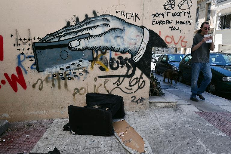 A man walks by a wall adorned with grafitti in Athens, Greece, on May 25, 2015