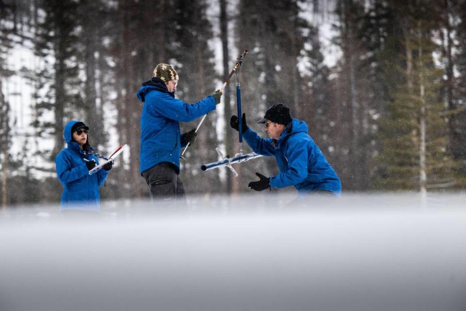 Hydrometeorologist Angelique Fabbiani-Leon, left, and water resources engineers Anthony Burdock and Andy Reising take measurements for the California Department of Water Resources as snow falls during a snow survey at Phillips Station in El Dorado County on Thursday, Feb. 29, 2024. The survey recorded 47.5 inches of snow depth and a snow water equivalent of 18 inches, which is 77% of normal.