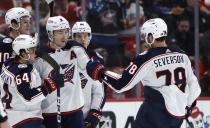 Columbus Blue Jackets defenseman Zach Werenski (8) is congratulated by defenseman Damon Severson (78), right wing Trey Fix-Wolansky (64) and others after scoring against the Detroit Red Wings during the first period of an NHL hockey game Tuesday, March 19, 2024, in Detroit. (AP Photo/Duane Burleson)