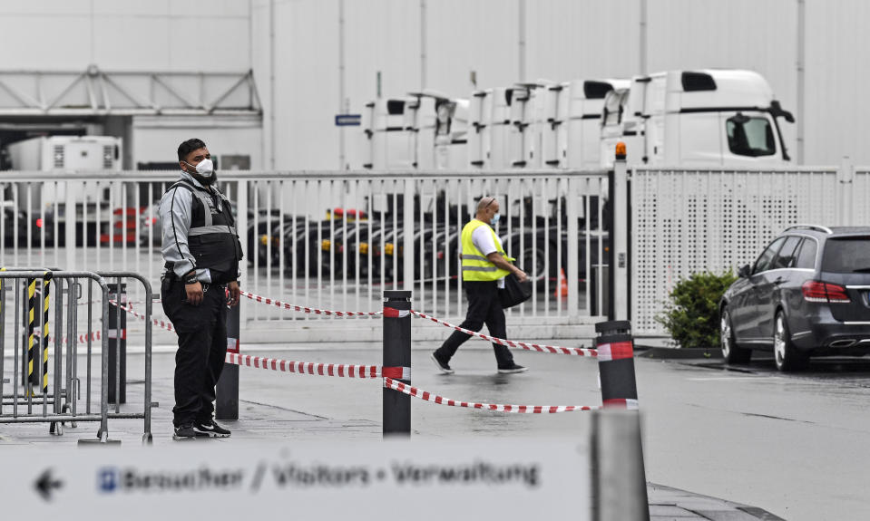 A member of the security stands in front of the Toennies meatpacking plant, Europe's biggest slaughterhouse, in Rheda-Wiedenbrueck, Germany, Thursday, June 18, 2020. Hundreds of new COVID-19 cases are linked to a large meatpacking plant, officials ordered the closure of the slaughterhouse, as well as isolation and tests for everyone else who had worked at the Toennies site — putting about 7,000 people under quarantine. (AP Photo/Martin Meissner)