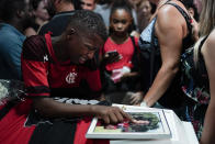 In this Feb. 9, 2019 photo, a friend, wearing a Flamengo soccer kit, grieves over the coffin containing the remains of the young soccer player Arthur Vinicius, one of the victims of a fire at a Brazilian soccer academy, during his funeral in Volta Redonda, Brazil. A fire early Friday swept through the sleeping quarters of an academy for Brazil's popular professional soccer club Flamengo, killing 10 people and injuring three, most likely teenage players, authorities said. (AP Photo/Leo Correa)