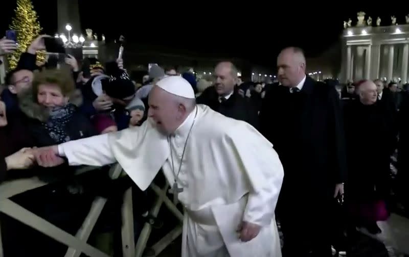 A woman grabs Pope Francis' hand and yanks him towards her, at Saint Peter's Square at the Vatican