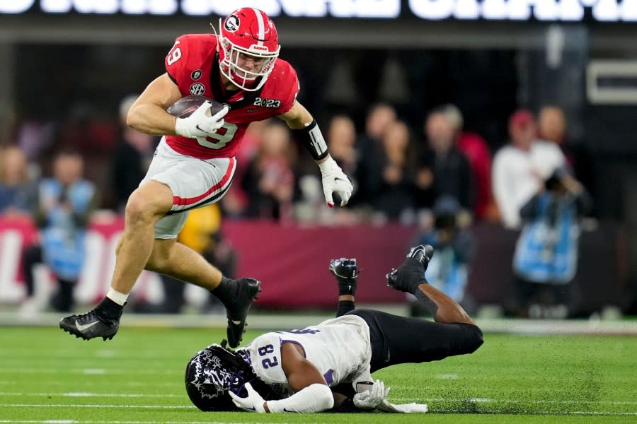 FILE – Georgia tight end Brock Bowers (19) leaps over TCU safety Millard Bradford (28) during the second half of the national championship NCAA College Football Playoff game, Monday, Jan. 9, 2023, in Inglewood, Calif. In three seasons at Georgia, Bowers caught 175 passes for 2,538 yards in 40 games and scored 31 total touchdowns with five of them coming as a runner as the Bulldogs did whatever they could to get the ball in his hands. (AP Photo/Ashley Landis, File)