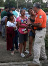 <p>A Mexican immigration worker speaks to Central American migrant women as he carries out out paperwork for migrants wishing to apply for refugee status in Mexico, as he canvases people participating in the Migrant Stations of the Cross caravan that has set up camp at a sports center in Matias Romero, Oaxaca state, Mexico, late Monday, April 2, 2018. (Photo: Felix Marquez/AP) </p>