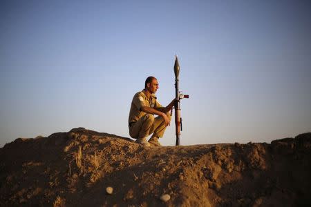 A Kurdish Peshmerga fighter keeps guard as his colleagues train before deploying to fight the Islamic State, at a temporary military camp near the frontline in Gwar, northern Iraq in this September 22, 2014 file photo. REUTERS/Ahmed Jadallah/Files