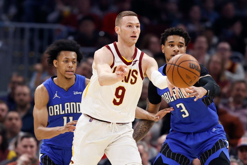 Cleveland Cavaliers' Dylan Windler (9) passes the ball against Orlando Magic's Chuma Okeke (3) and Jeff Dowtin (11) during the first half of an NBA basketball game, Monday, March 28, 2022, in Cleveland. (AP Photo/Ron Schwane)