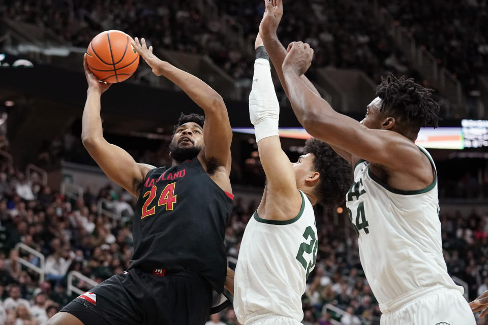 Maryland forward Donta Scott (24) is defended by Michigan State forward Malik Hall, center, and forward Julius Marble II during the first half of an NCAA college basketball game, Sunday, March 6, 2022, in East Lansing, Mich. (AP Photo/Carlos Osorio)