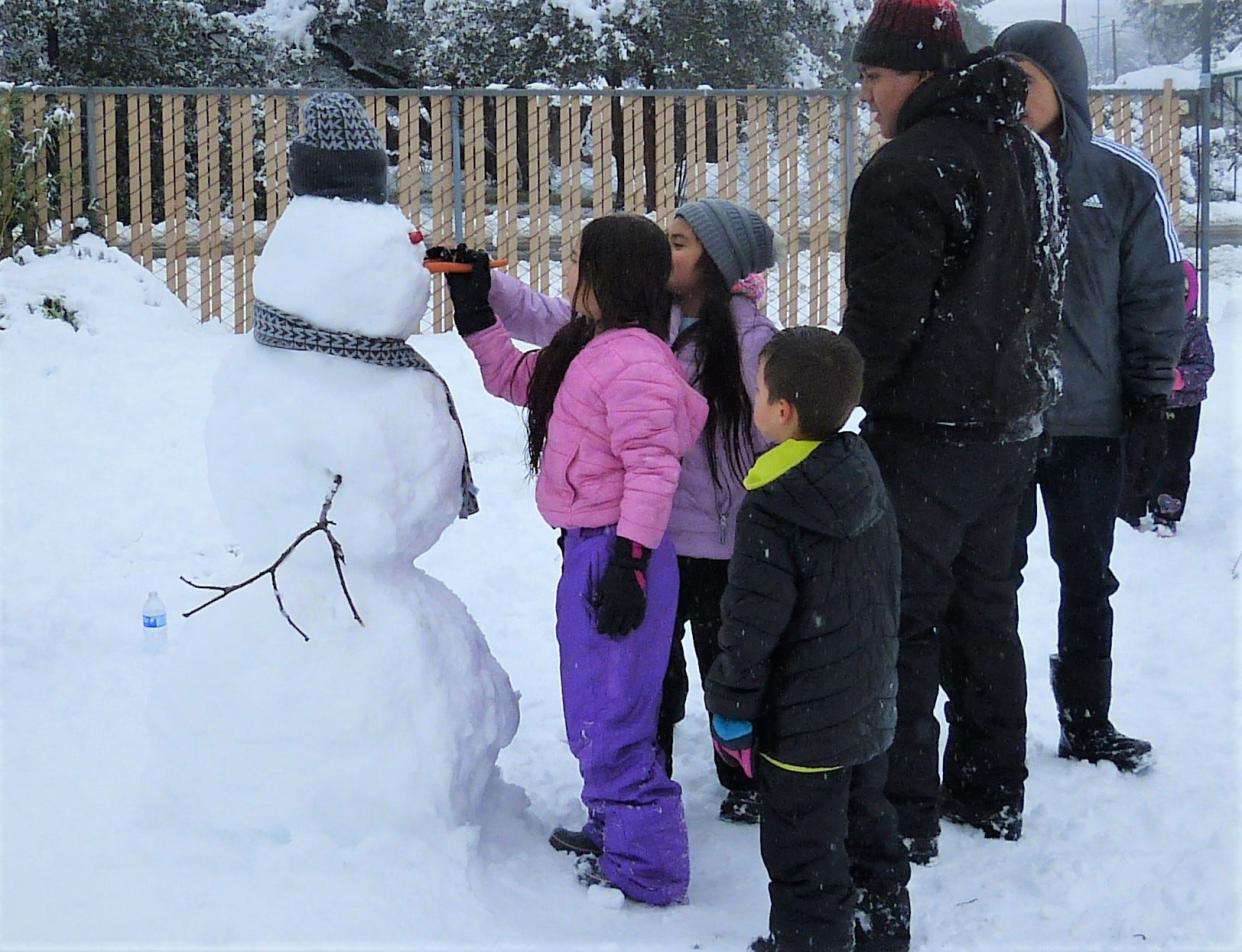 A Redding family gives a snowman a fresh carrot nose Friday.